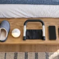 Fall prevention items arranged beside a senior bed including slippers, night light, and bed rail handle