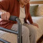 Older adult using a padded bed rail while standing with arthritis-related stiffness